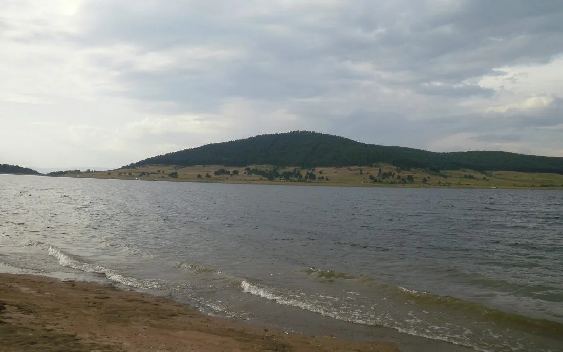 Гористият хълм на Баташката планина над водата на язовира