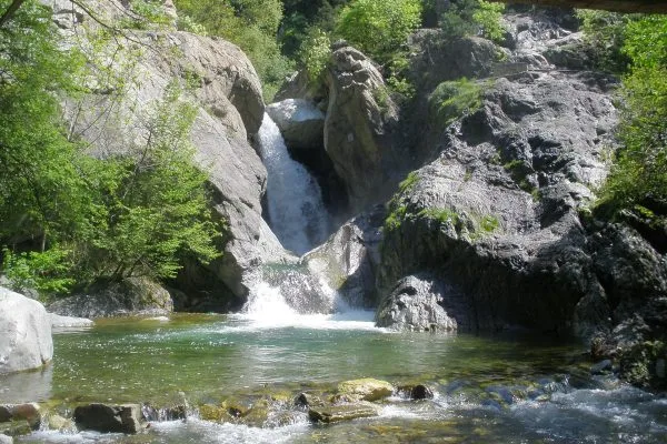 Широк изглед към водопада Сучурум и заобикалящите го зелени скали