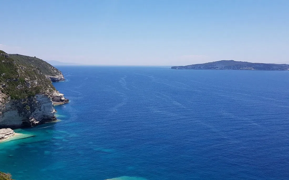 Белите скали на Паксос над Йонийско море със силуета на Антипаксос