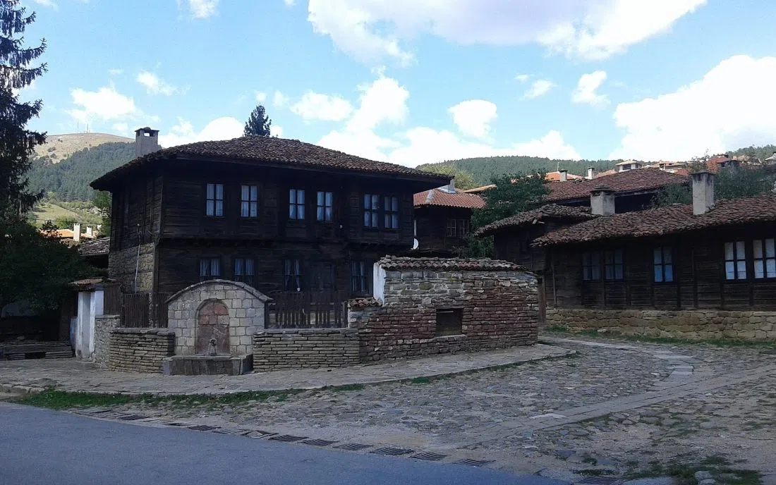 Калдъръмена улица с възрожденски дървени къщи и каменна чешма в стария център на Котел