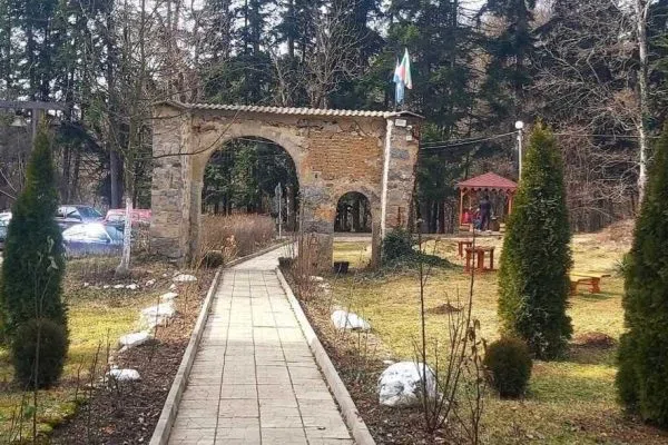 Каменната сводеста порта към Искрецкия манастир между подрязаните туи