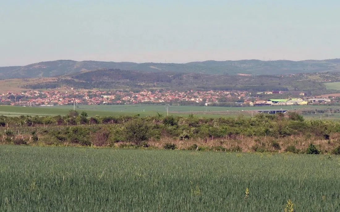 Панорама на Българово сред зелени житни ниви с балкански хълмове на хоризонта