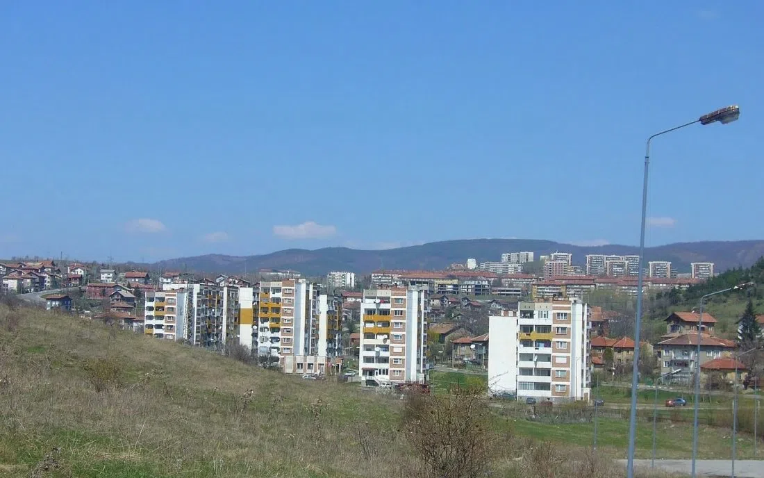 Жилищни блокове на Бобов дол сред зеленина с хълмове на заден план