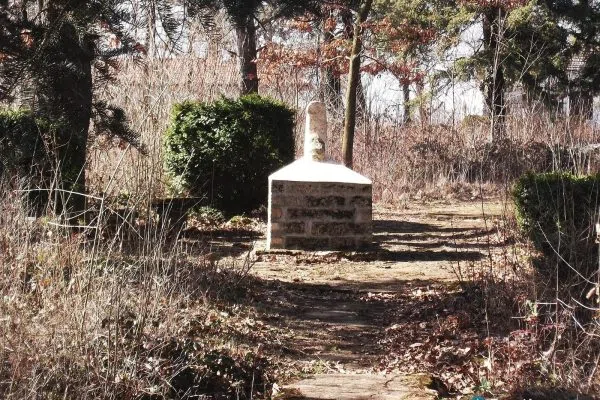 Скромен каменен паметник в горист парк край Долни Дъбник