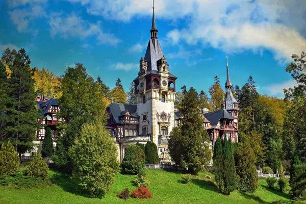 Приказният замък Пелеш с островърхи кули сред карпатската гора в Синая